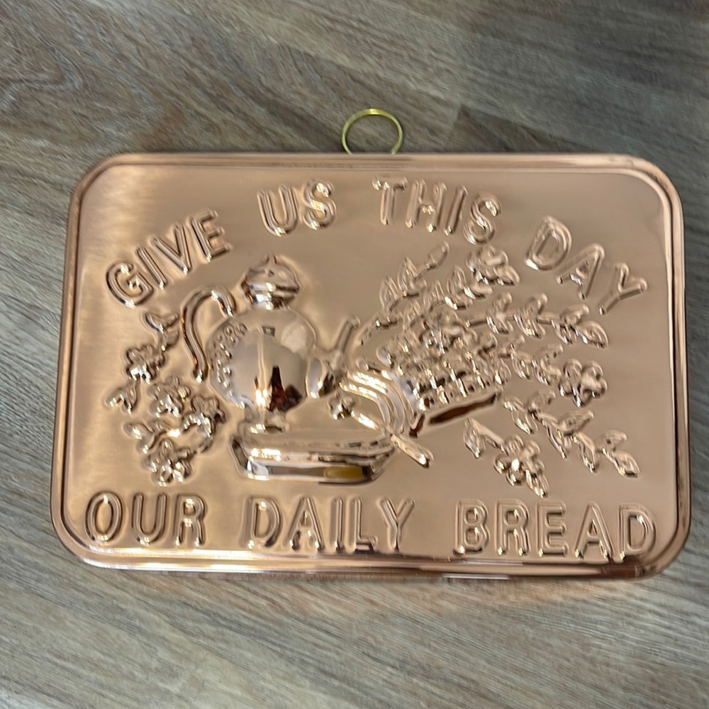 Rectangular copper piece that reads “Give Us This Day Our Daily Bread”
